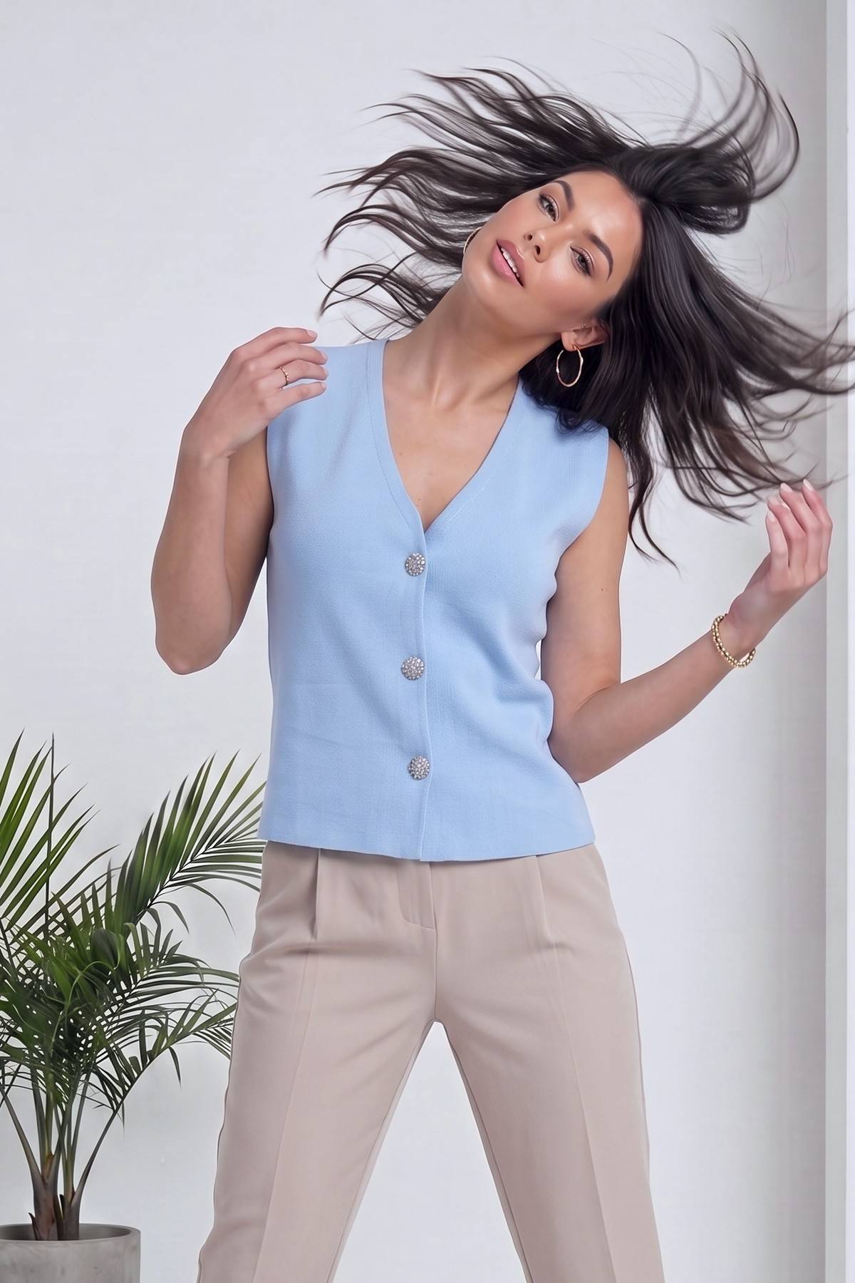 The ZKS bebe mavisi V yaka kolsuz triko yelek modelin enerjik duruşu, saçları havada