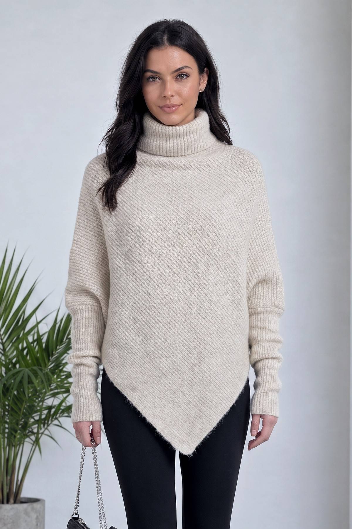 Bej boğazlı kazak, önü kısa arkası uzun asimetrik kesimiyle modern bir stil sunuyor.
