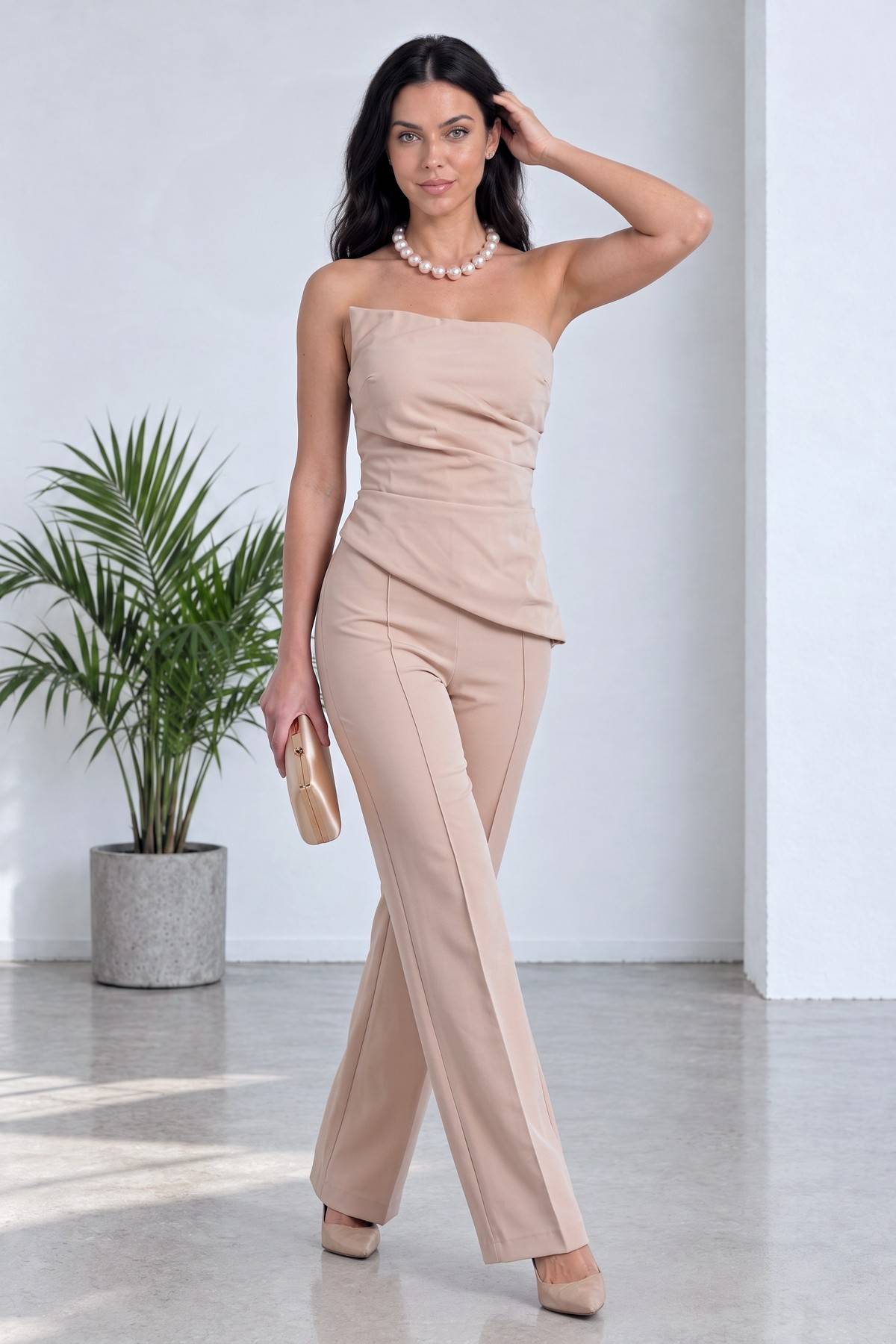 The ZKS bej straplez bluz ve flare pantolon ikili takımın tam ön duruşu, modelin elinde gold portföy çanta ile poz veriyor