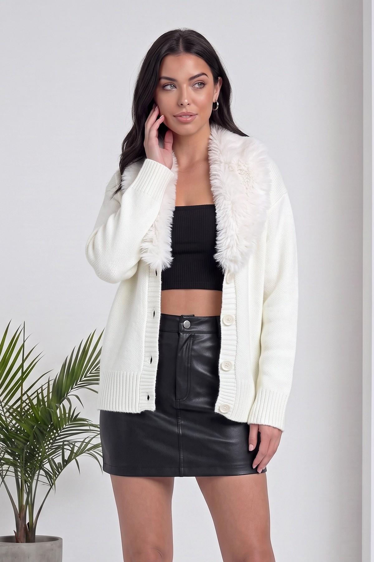 The ZKS beyaz kürk yakalı hırka, siyah crop top ve deri mini etek ile kombinlenmiş