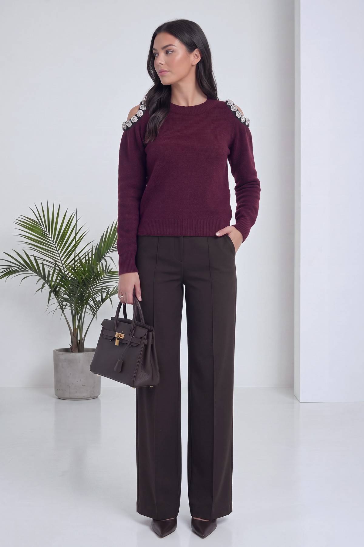 Model, bordo omuz detaylı triko kazağını ve koyu renk geniş paça pantolonunu sergiliyor, yandan görünüm.