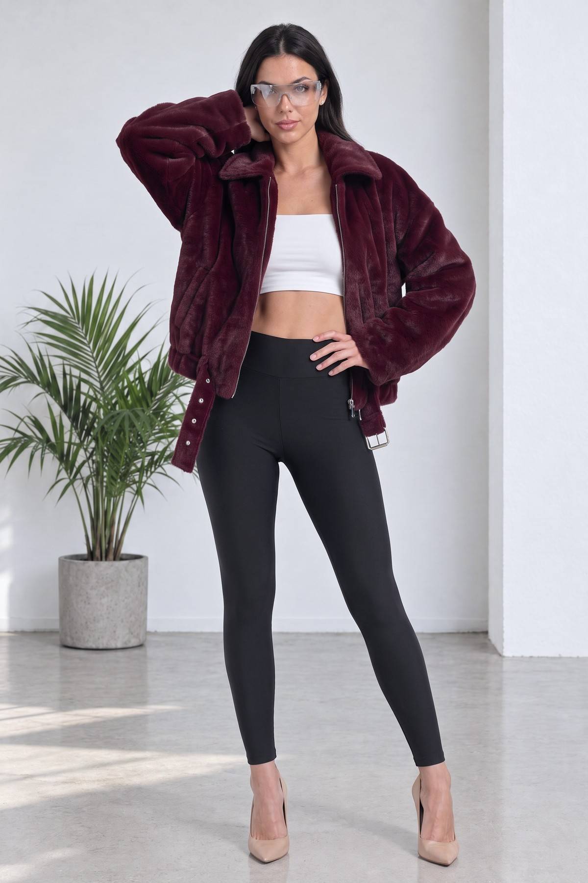 Model bordo fermuarlı bomber ceketiyle ayakta, beyaz crop top ve tayt ile kombinlenmiş