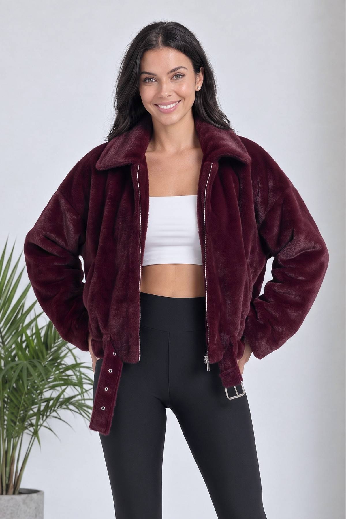 Bordo fermuarlı bomber ceket, beyaz crop top ve siyah tayt ile kombinlenmiş, modelin duruşu