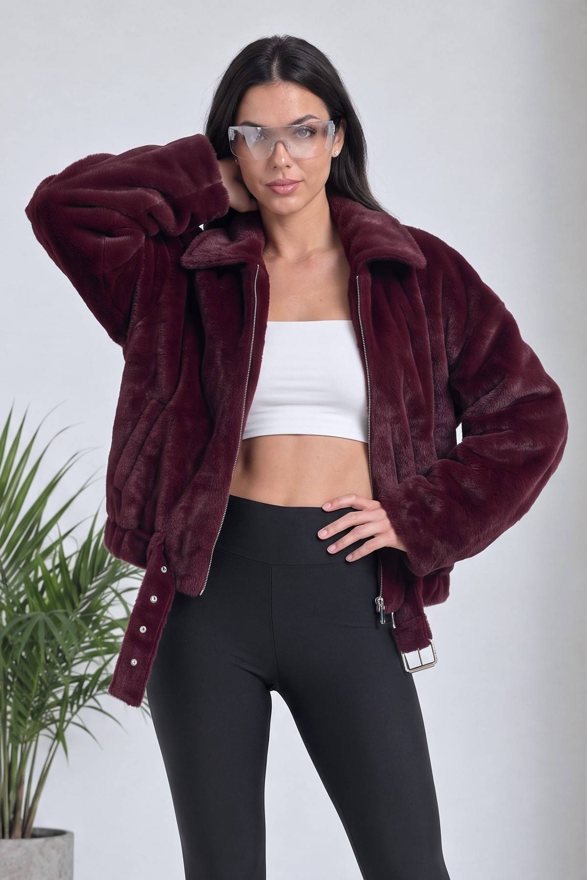 Model, gözlük takarak bordo bomber ceketiyle poz veriyor, crop top ve tayt kombinli