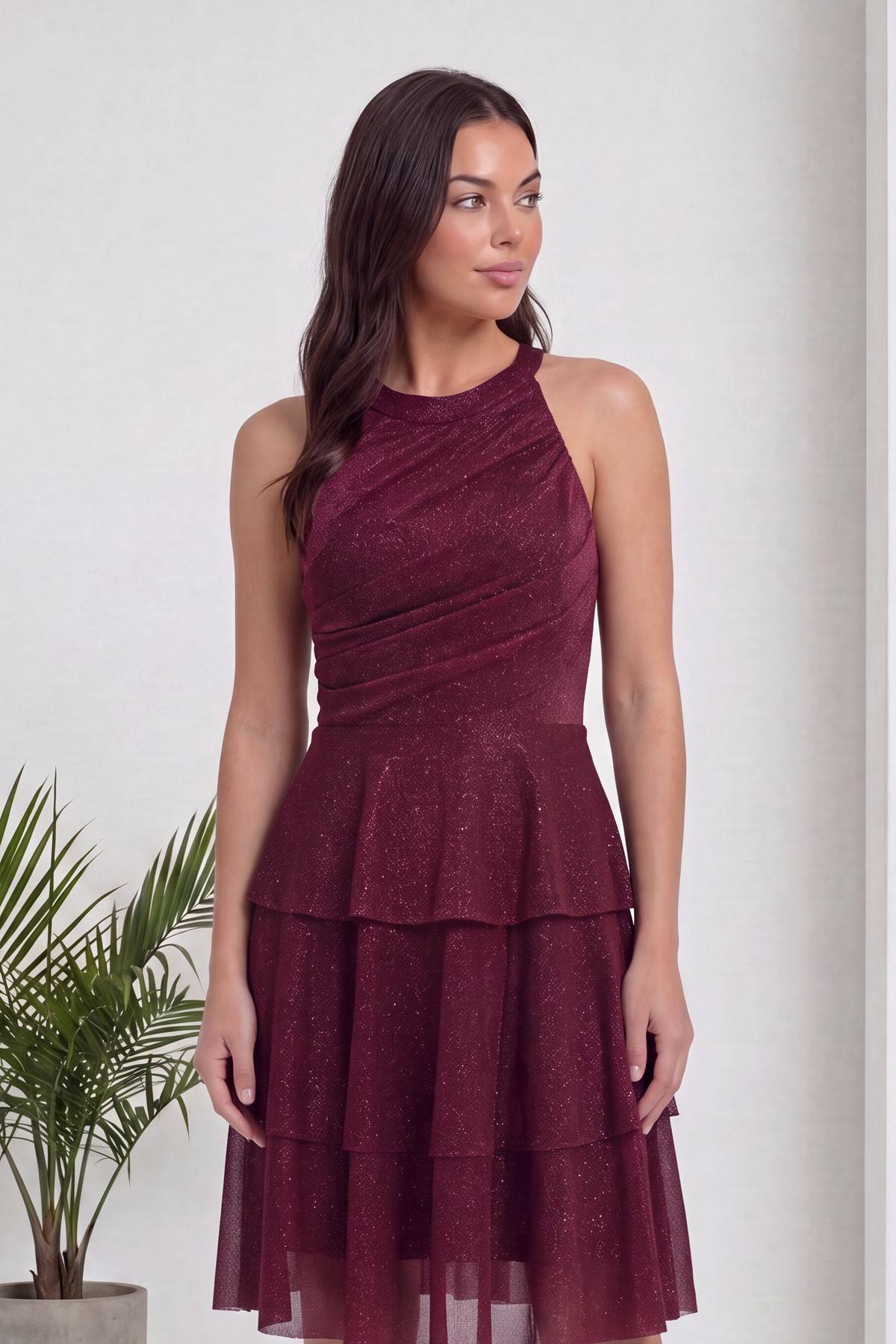 Bordo halter yaka kısa elbise, parlak simli kumaşı ve büzgülü üst kısmı vurguluyor