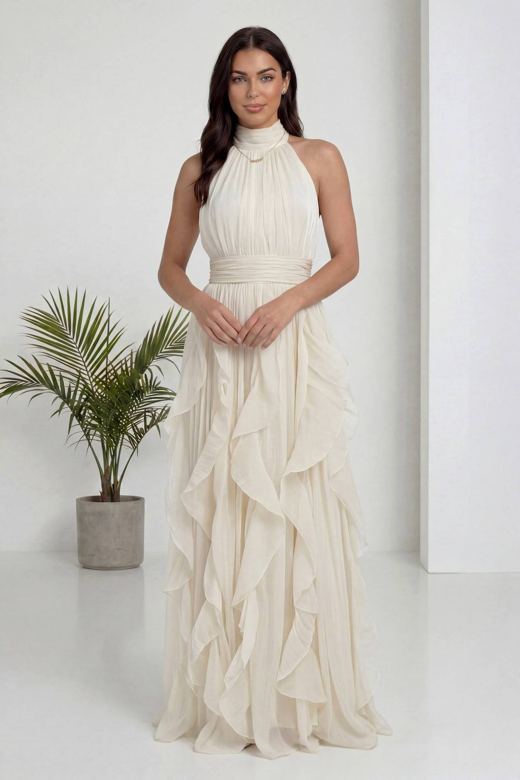 Ekru halter yaka fırfırlı uzun abiye elbise, eller önde kavuşmuş, zarif duruş