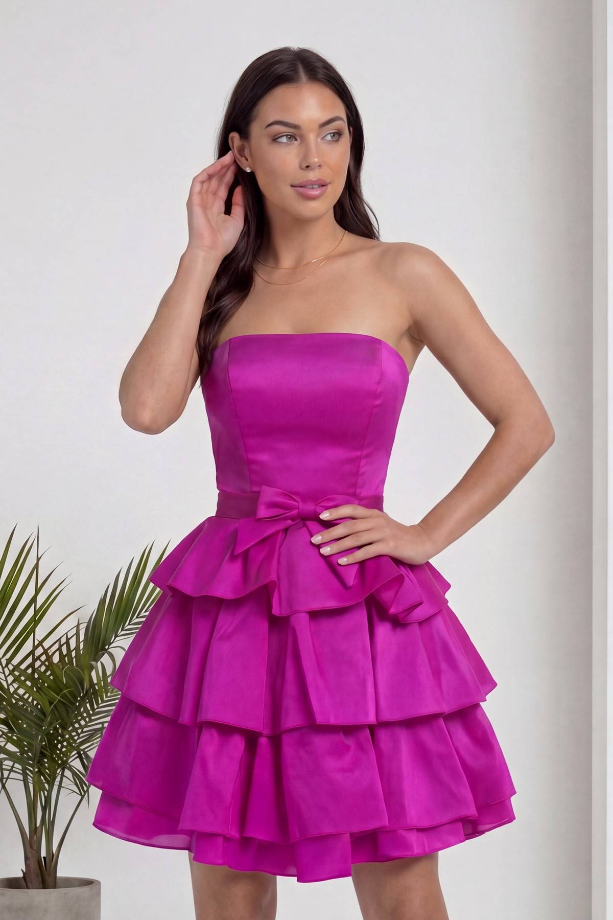 Fuşya straplez elbise modeli, kulağına dokunurken çekilmiş, elbisenin dokusu ve kalıbı seçiliyor