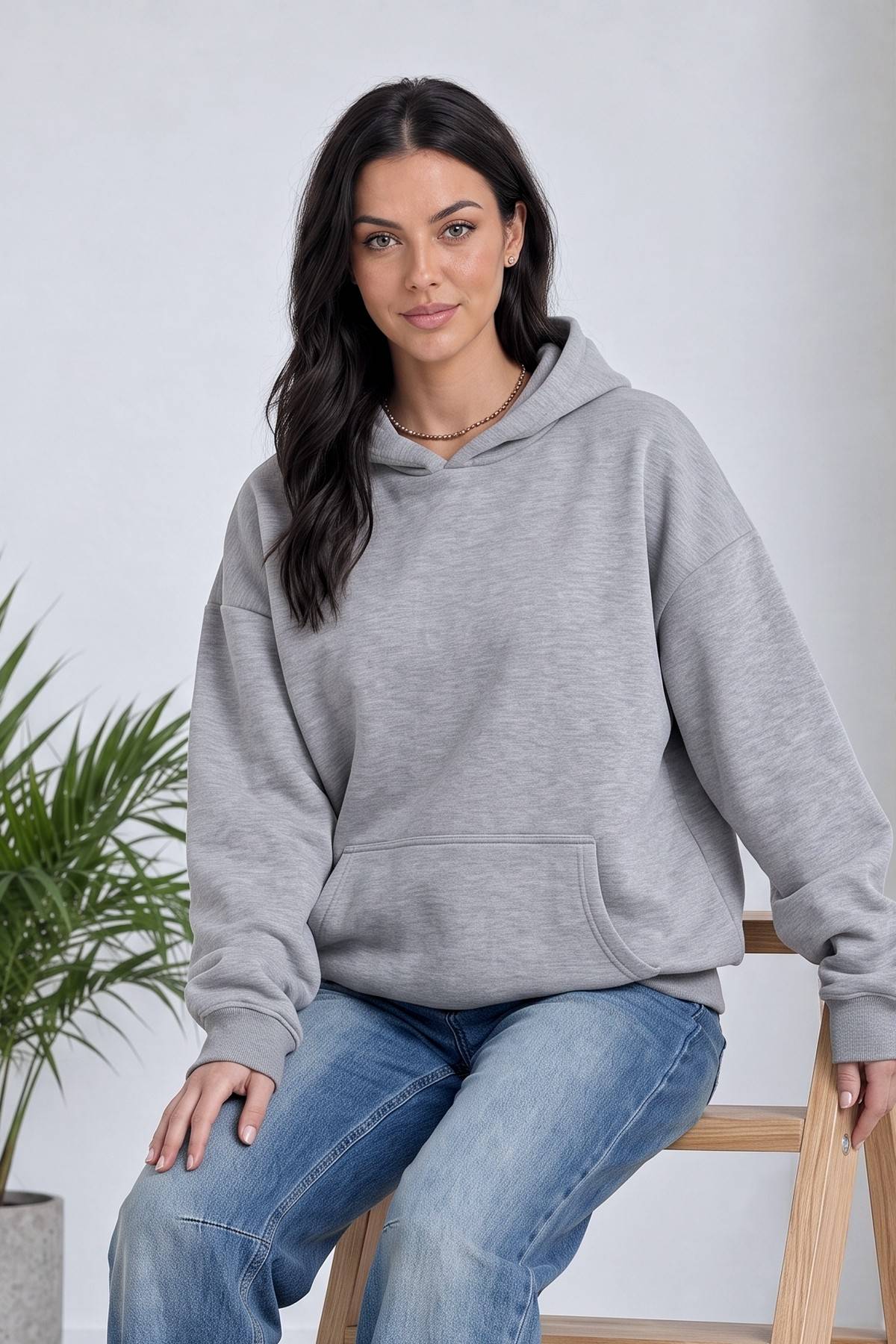 Model, The ZKS gri kapüşonlu sweatshirt ile otururken hafifçe yandan görünüm