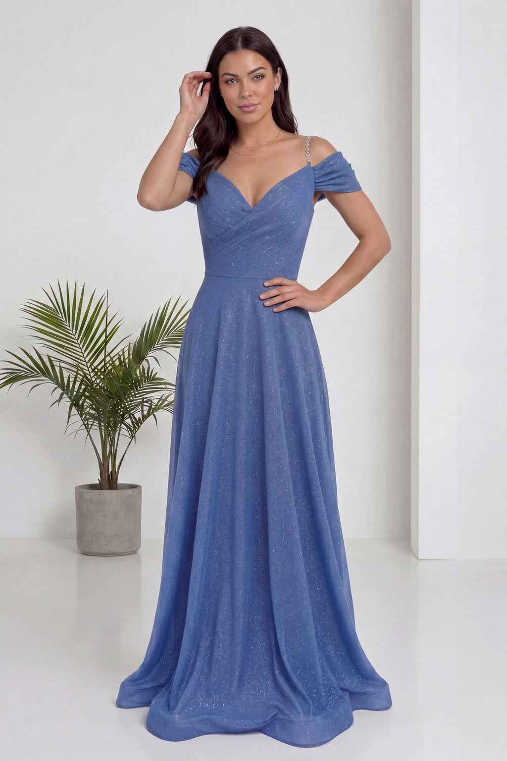 The ZKS indigo rengi, düşük omuzlu, simli, piliseli uzun abiye elbise ön görünüm, model elini beline koymuş