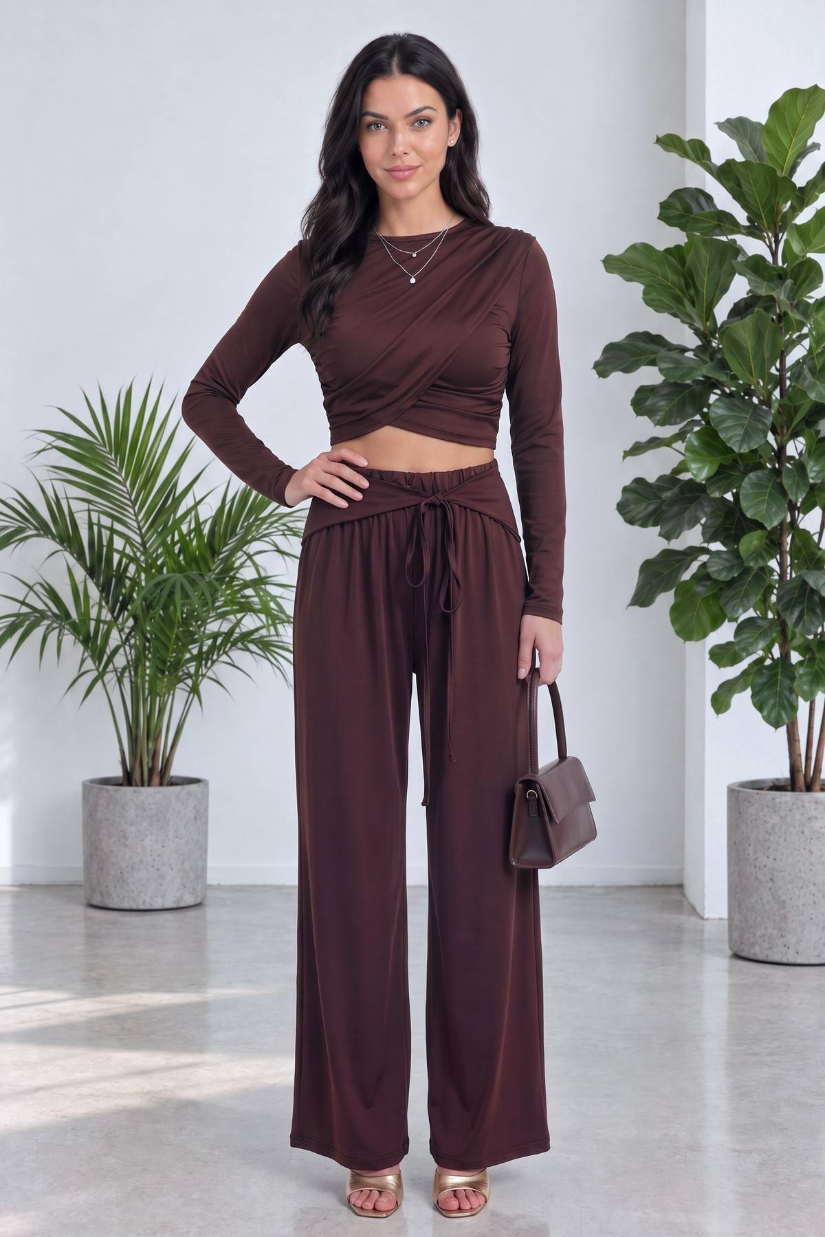 Kahverengi crop bluz ve geniş paça pantolon takımı giymiş model, tam boy duruş