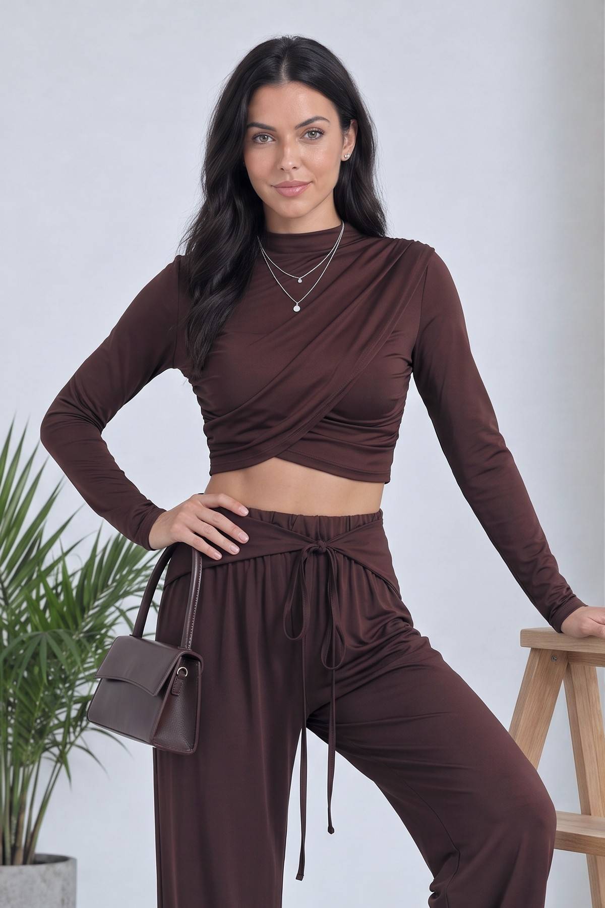 Kahverengi crop bluz ve geniş paça pantolon takımı giymiş model, yandan duruş detayı