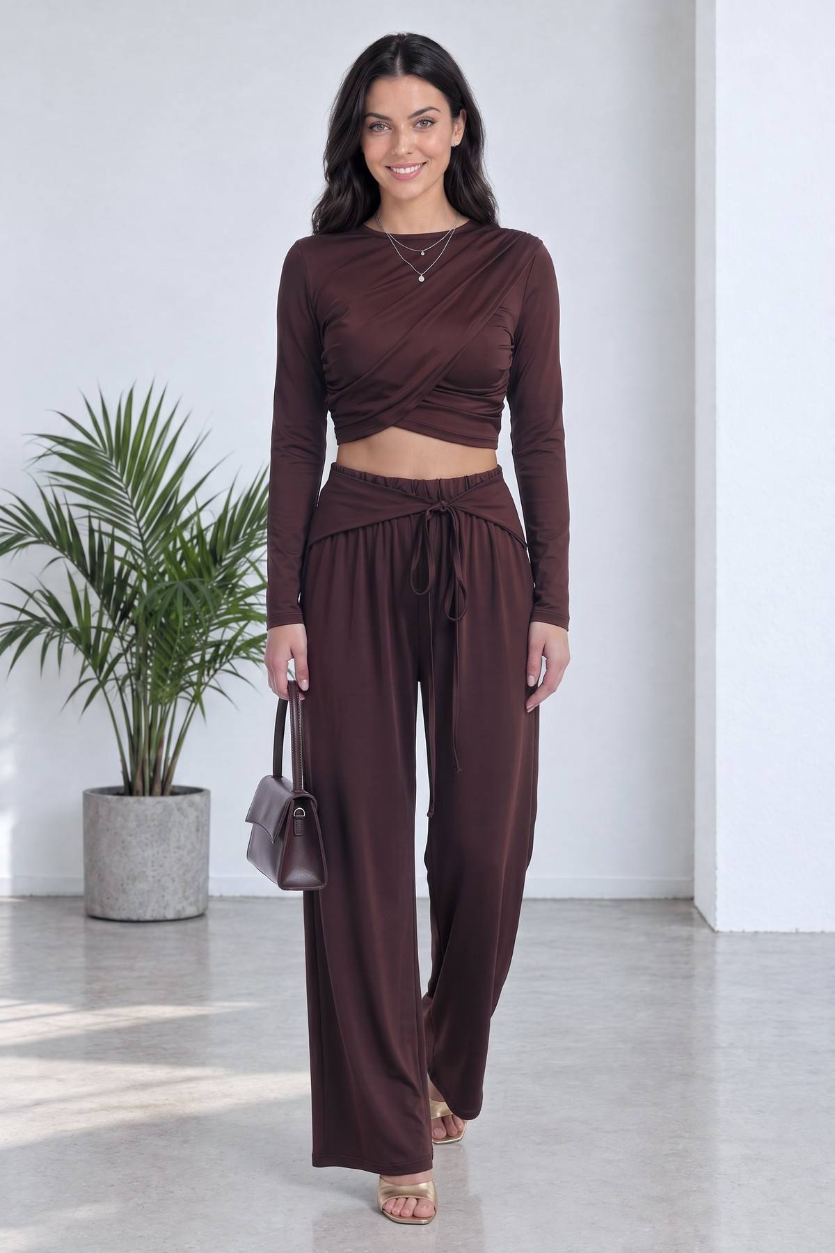 Kahverengi crop bluz ve geniş paça pantolon takımı giymiş model, ayakta duruş