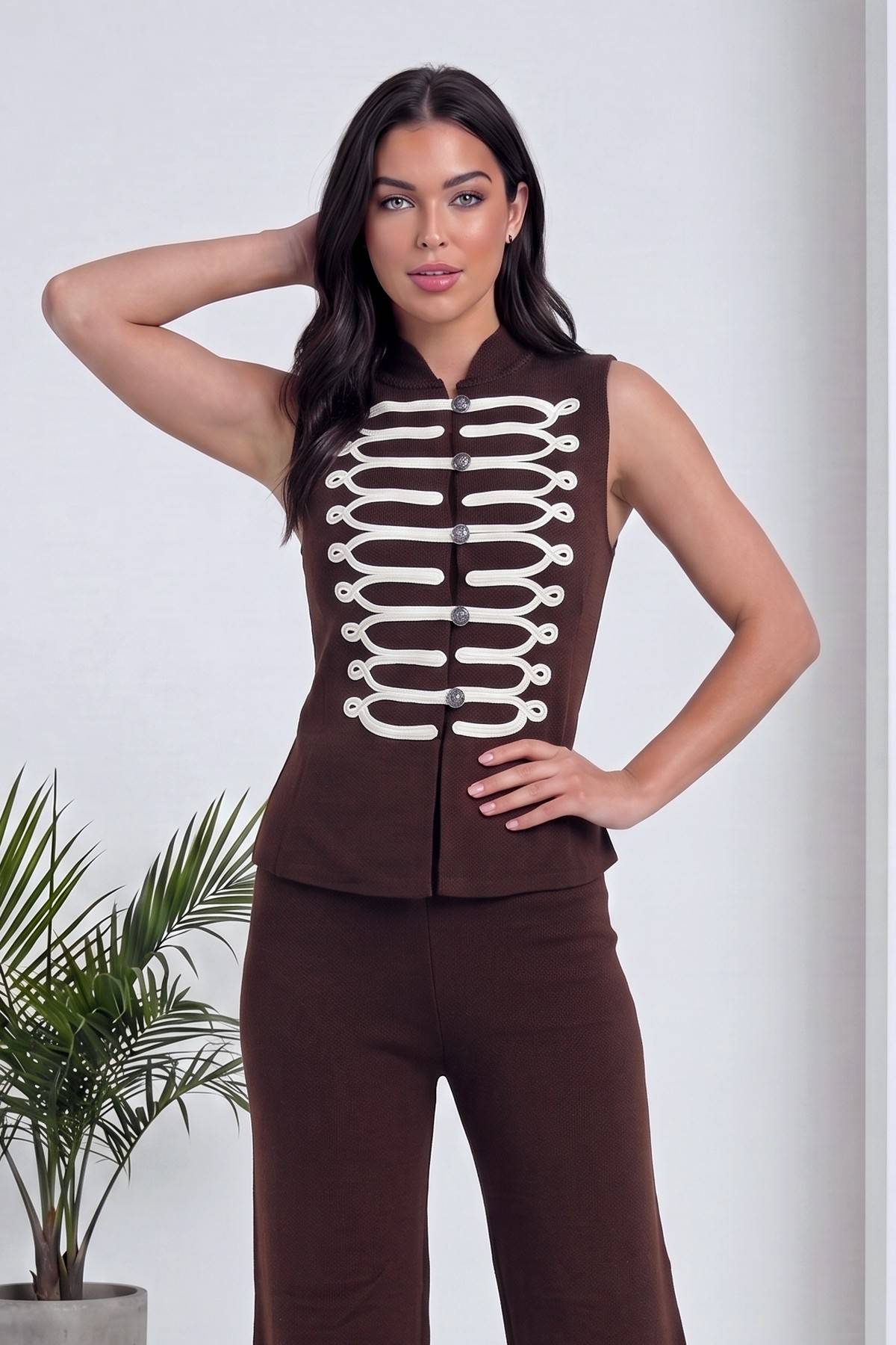 The ZKS Napolyon detaylı kolsuz yelek ve yüksek bel pantolon ikili takım kahverengi, yelek önü beyaz ip şeritli ve düğmeli, yan duruş, el belde