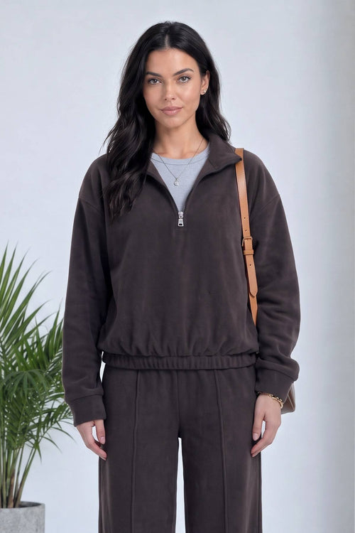 Model kahverengi ZKS yarım fermuarlı sweatshirt ve geniş paça pantolon ile poz veriyor