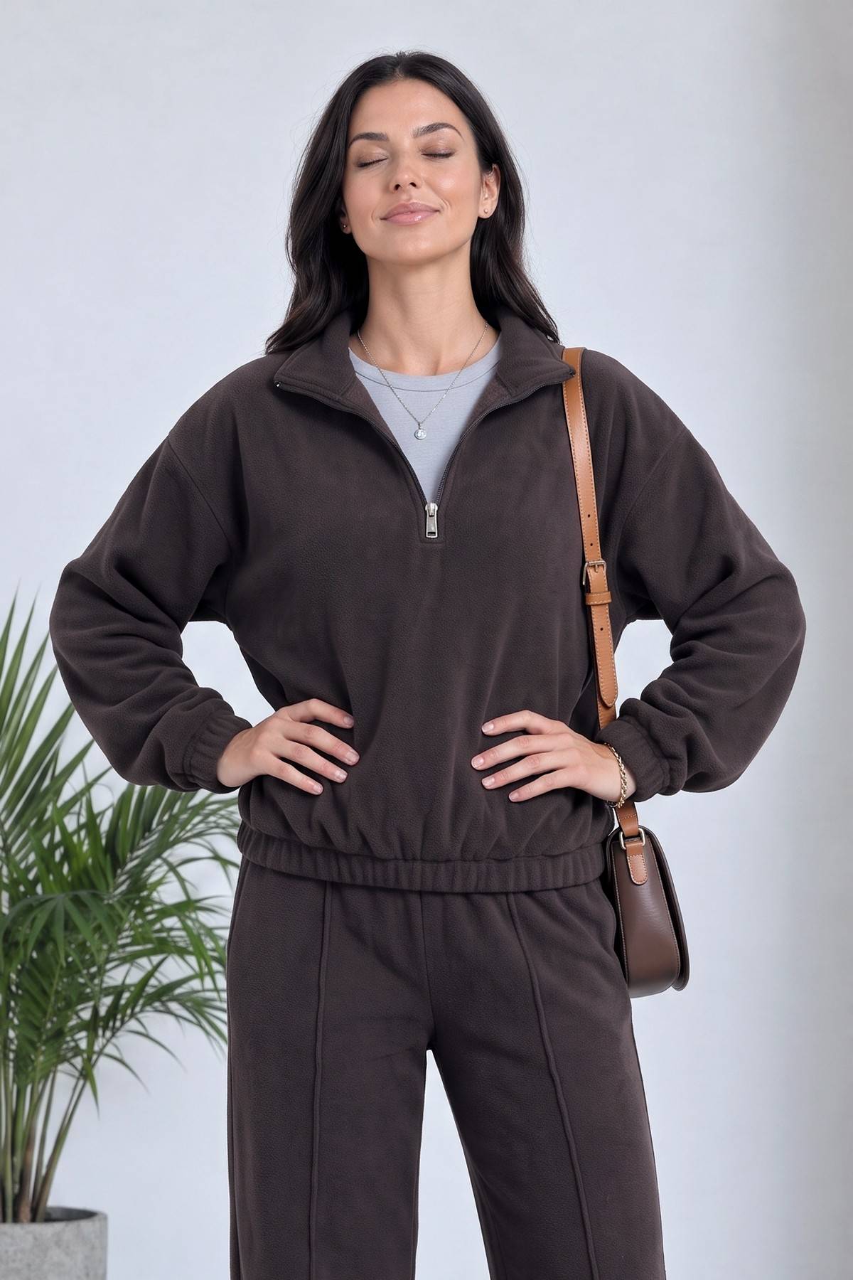 Kadın kahverengi ZKS yarım fermuarlı sweatshirt ve geniş paça pantolon kombiniyle duruyor