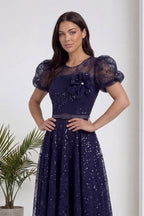 Lacivert dantel midi abiye elbise, yuvarlak yaka, çiçek broş ve kemer detayıyla önden görünüm.