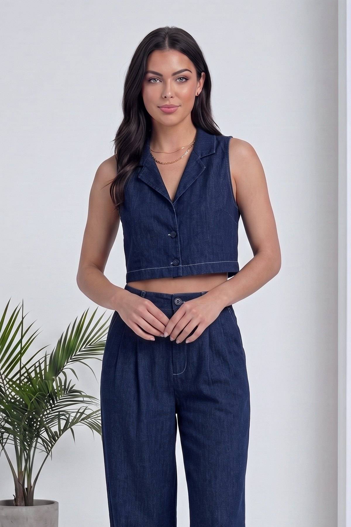 Lacivert yelek ve pantolon takımının ön görünümü, modelin elleri önünde birleşik