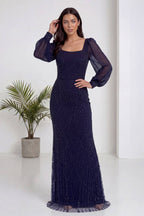 Lacivert kare yaka şifon kollu, balık kesim, işlemeli abiye elbise modelin elini saçına götürdüğü poz