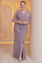 Modelin elleri önünde birleşmiş, The ZKS lila büyük beden abiye elbisenin ön detayları ve şifon kolları belirgin