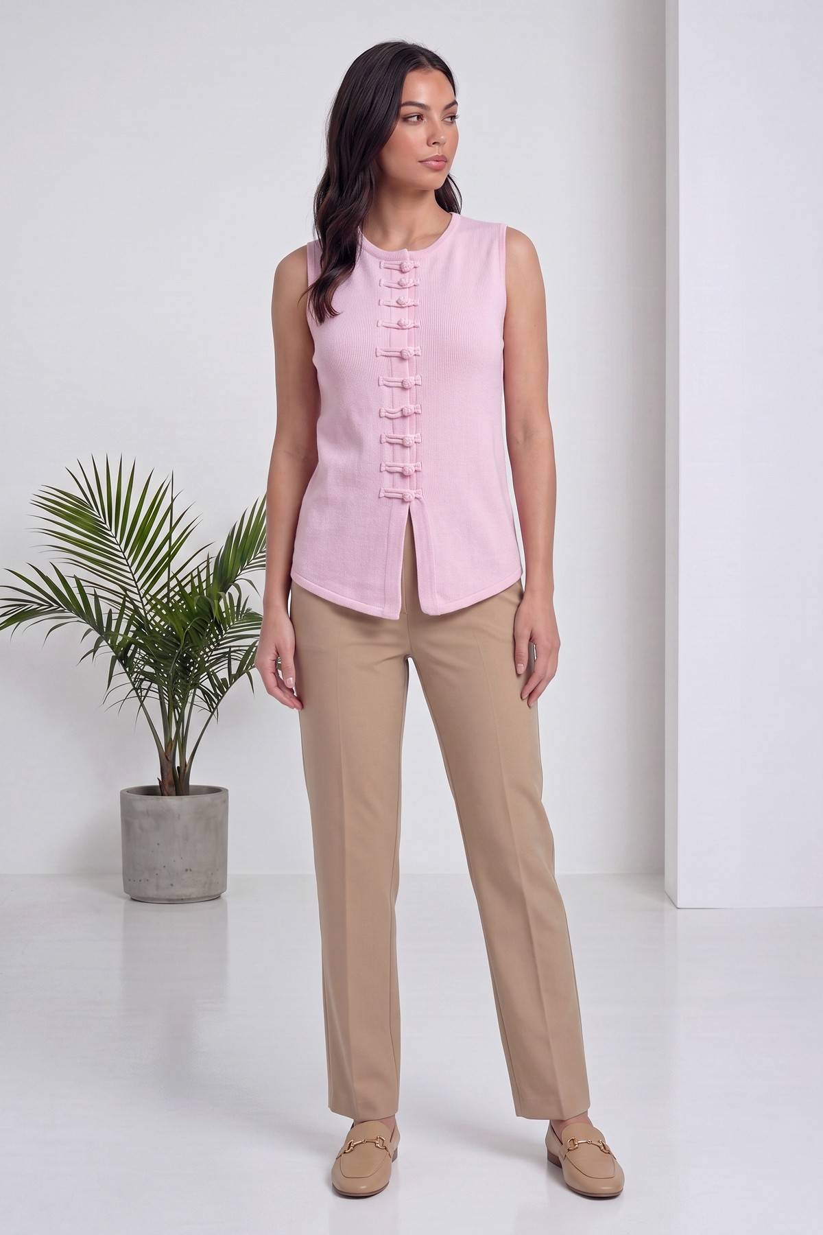 The ZKS pembe triko bluz, ayakta duruşu, pantolonla kombinlenmiş şık bir stil.