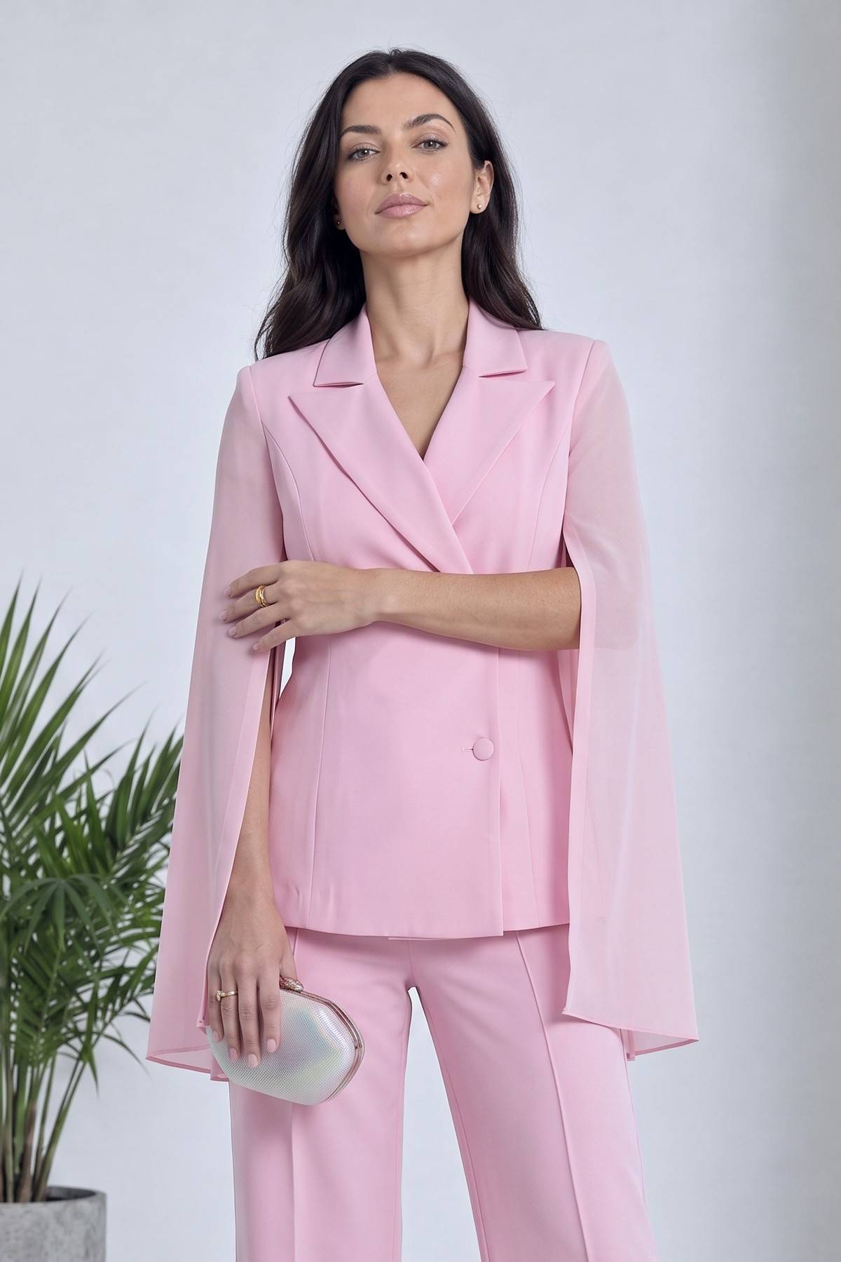 Pembe şifon kollu kruvaze ceket ve düz paça pantolon takımı, modelin el ve ceket detayı