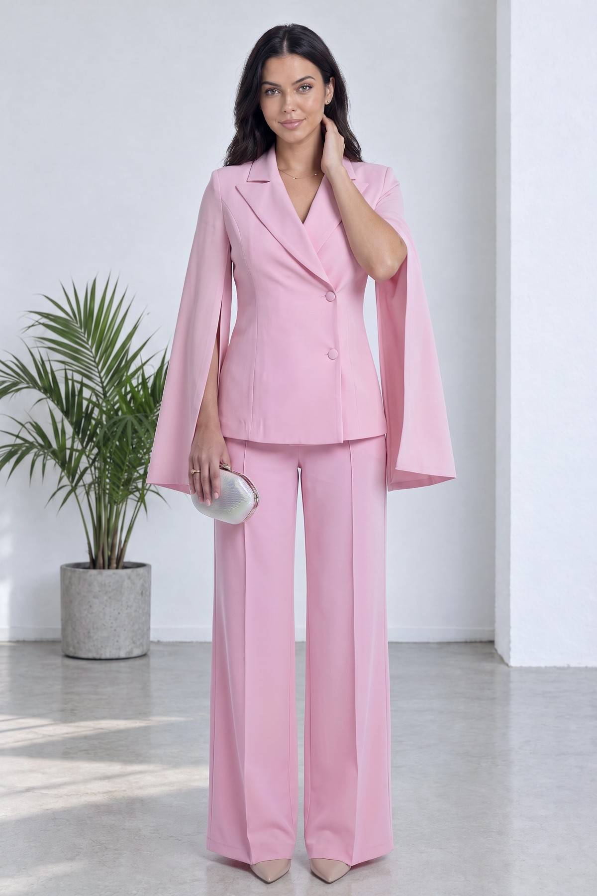 Pembe şifon kollu kruvaze ceket ve düz paça pantolon takımı, modelin duruşu ve aksesuar detayı