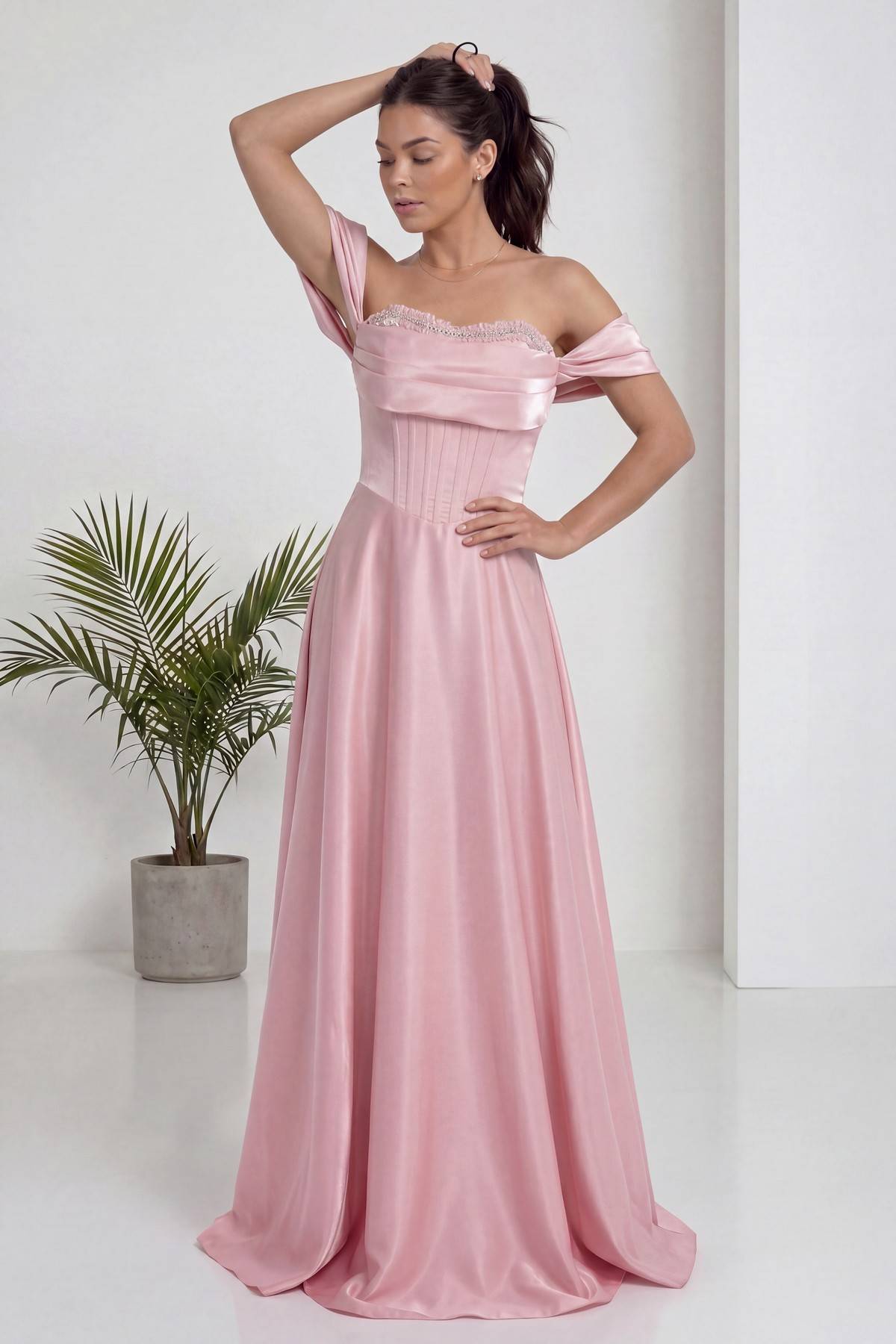 Pembe prenses kesim The ZKS abiye, düşük omuzlu, korseli ve taş detaylı, modelin kolunu kaldırdığı duruş
