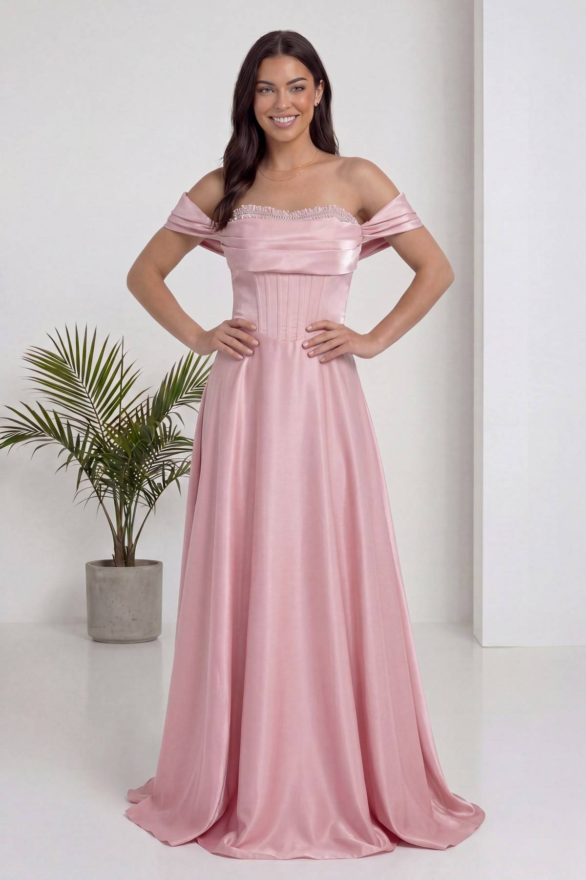 Pembe The ZKS abiye, korseli ve taşlı yaka detayı, modelin elleri belinde duruşu, ön görünüm