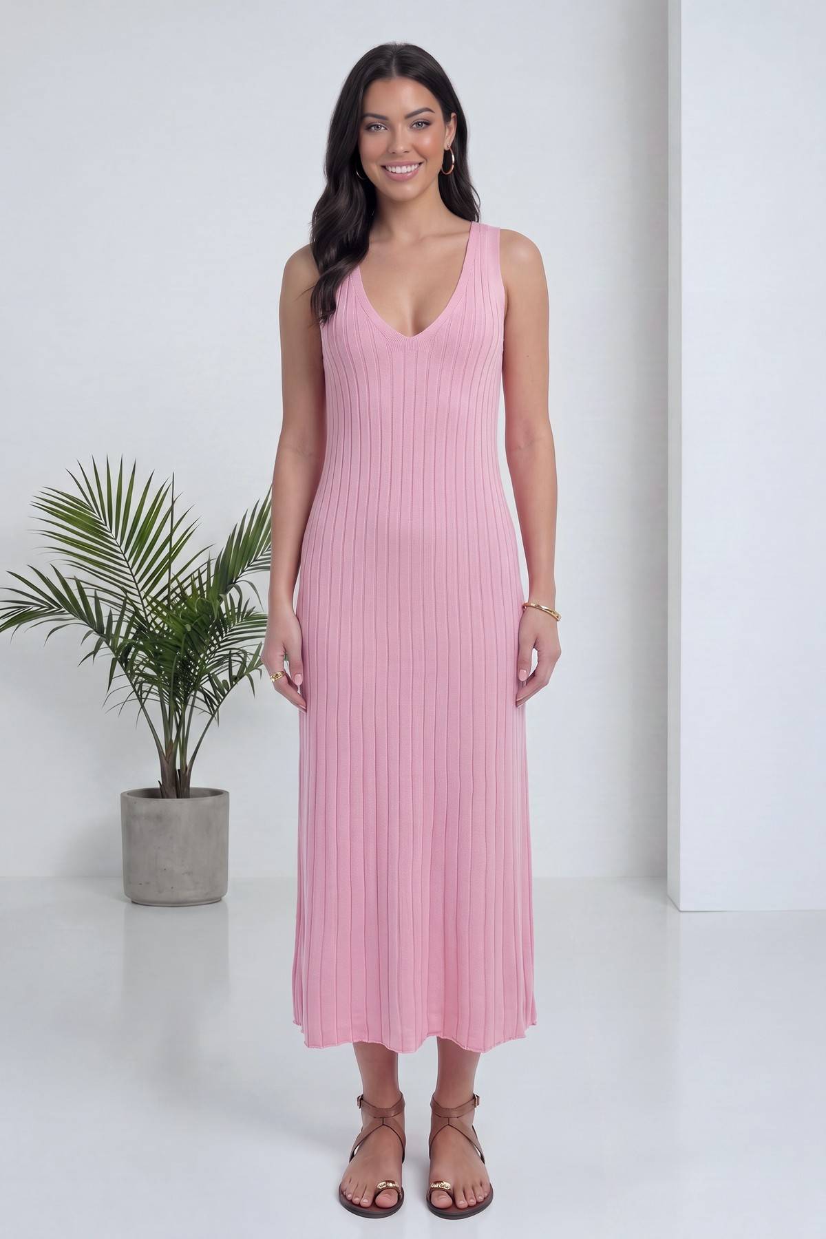 Modelin üzerinde pembe V yaka fitilli triko midi elbise, ön cepheden gülümseyen ifade.