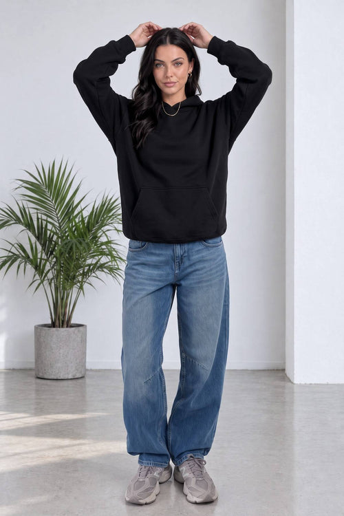 Model, The ZKS siyah kapüşonlu sweatshirt ve geniş paça kot pantolon ile önden duruyor