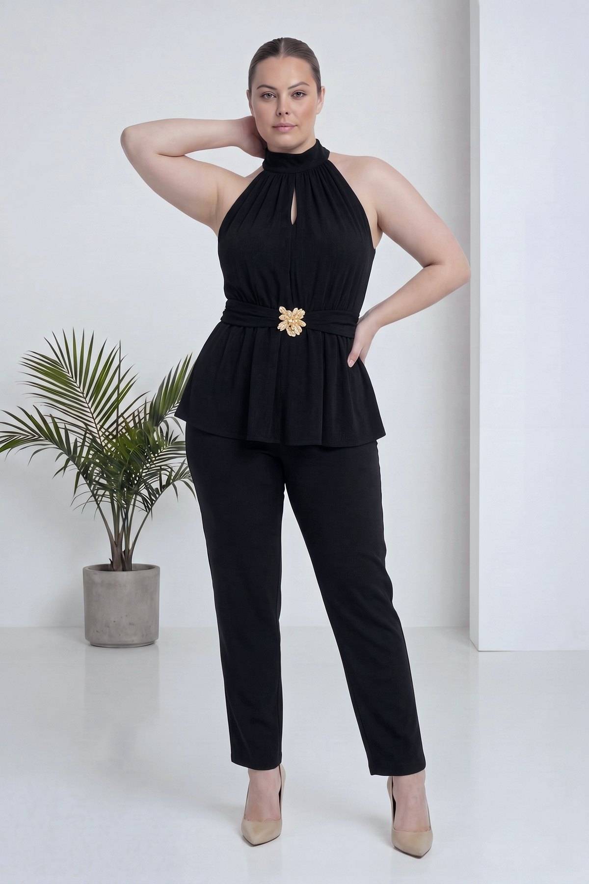 Modelin elinde çiçekli kemer detayıyla büyük beden siyah halter yaka bluz ve pantolon