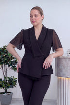 Büyük beden siyah takımın kruvaze ceketinin ön detayı, taş işlemeleri ve kruvaze kesimi belirgin, yan duruş