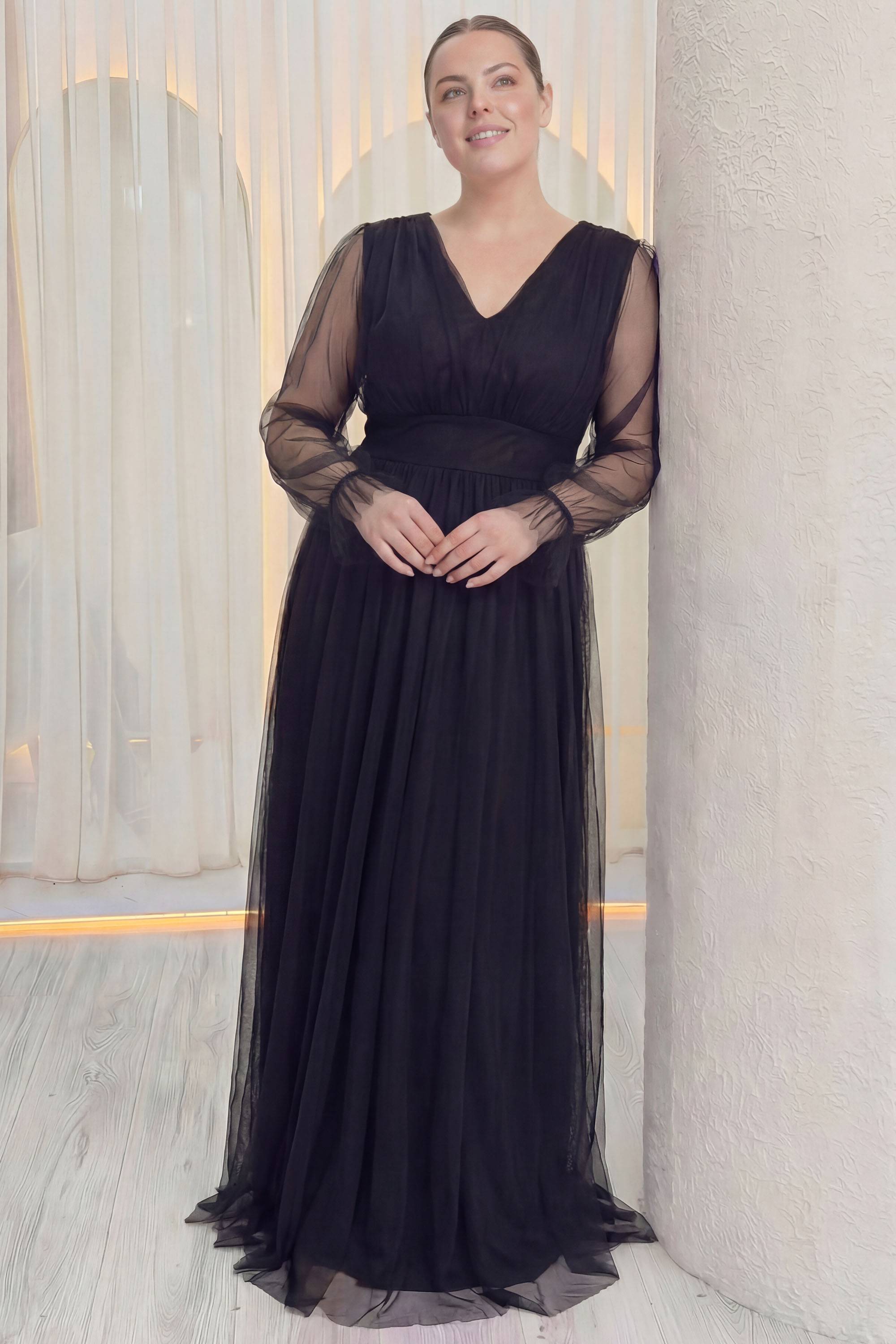 ZKS büyük beden siyah tül abiye elbise, duvara yaslanmış, V yaka, beli vurgulayan kemer