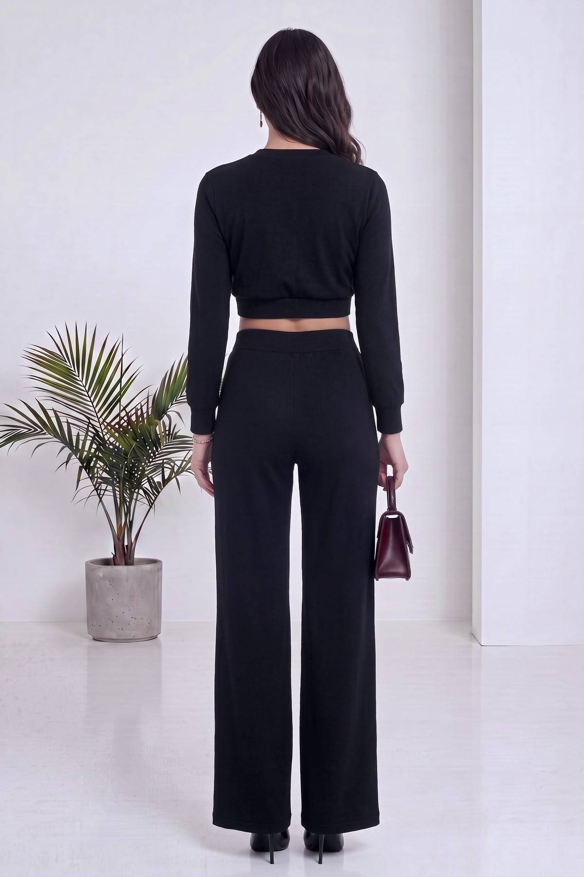 Siyah kruvaze crop bluz ve beli büzgülü bol paça pantolon ikili takımın arkadan görünümü