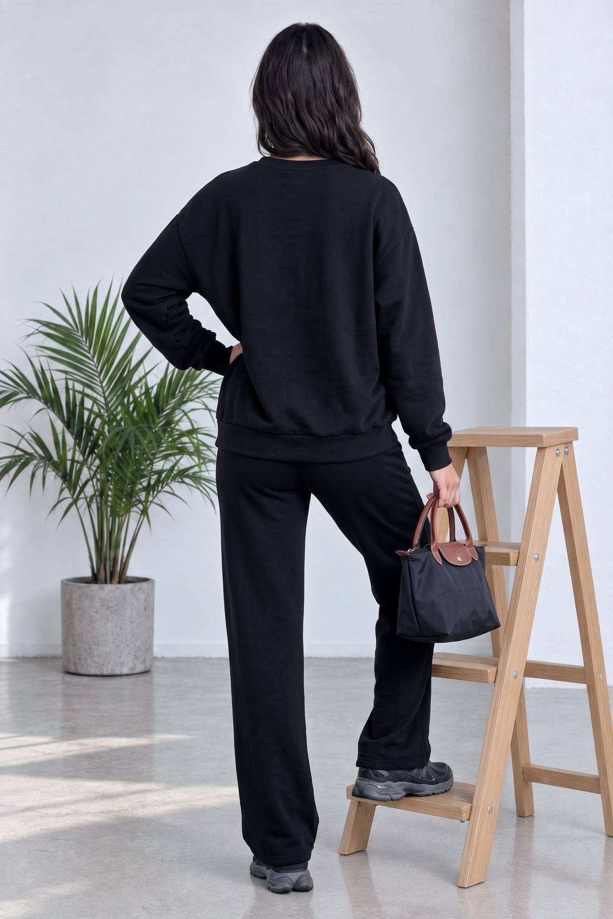 The ZKS siyah yarım fermuarlı sweatshirt ve geniş paça pantolon kombini arkadan görünüm, model ayakta duruyor