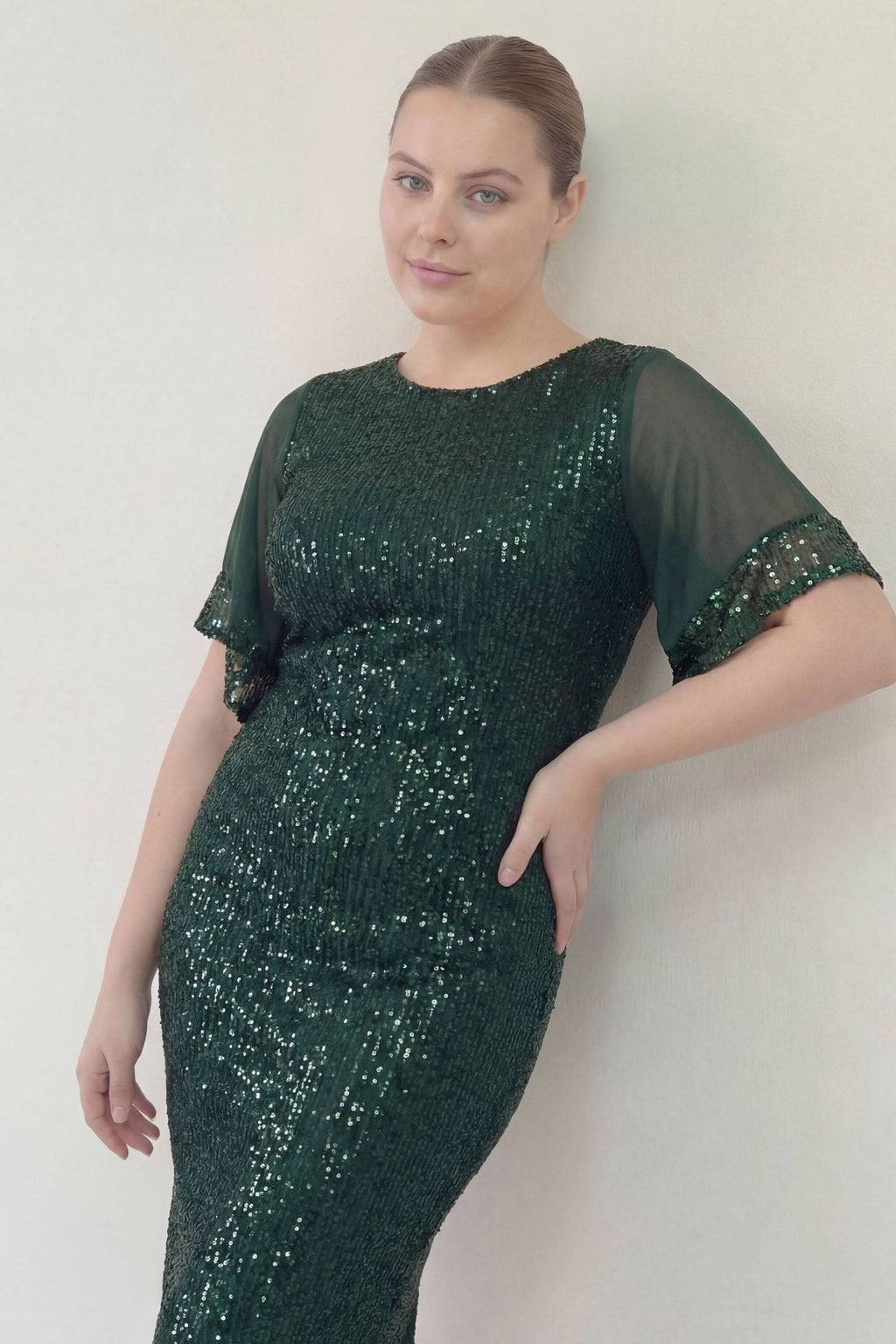 ZKS büyük beden yeşil pulpayet midi abiye elbise, şeffaf kollu, duvara yaslanmış şık poz