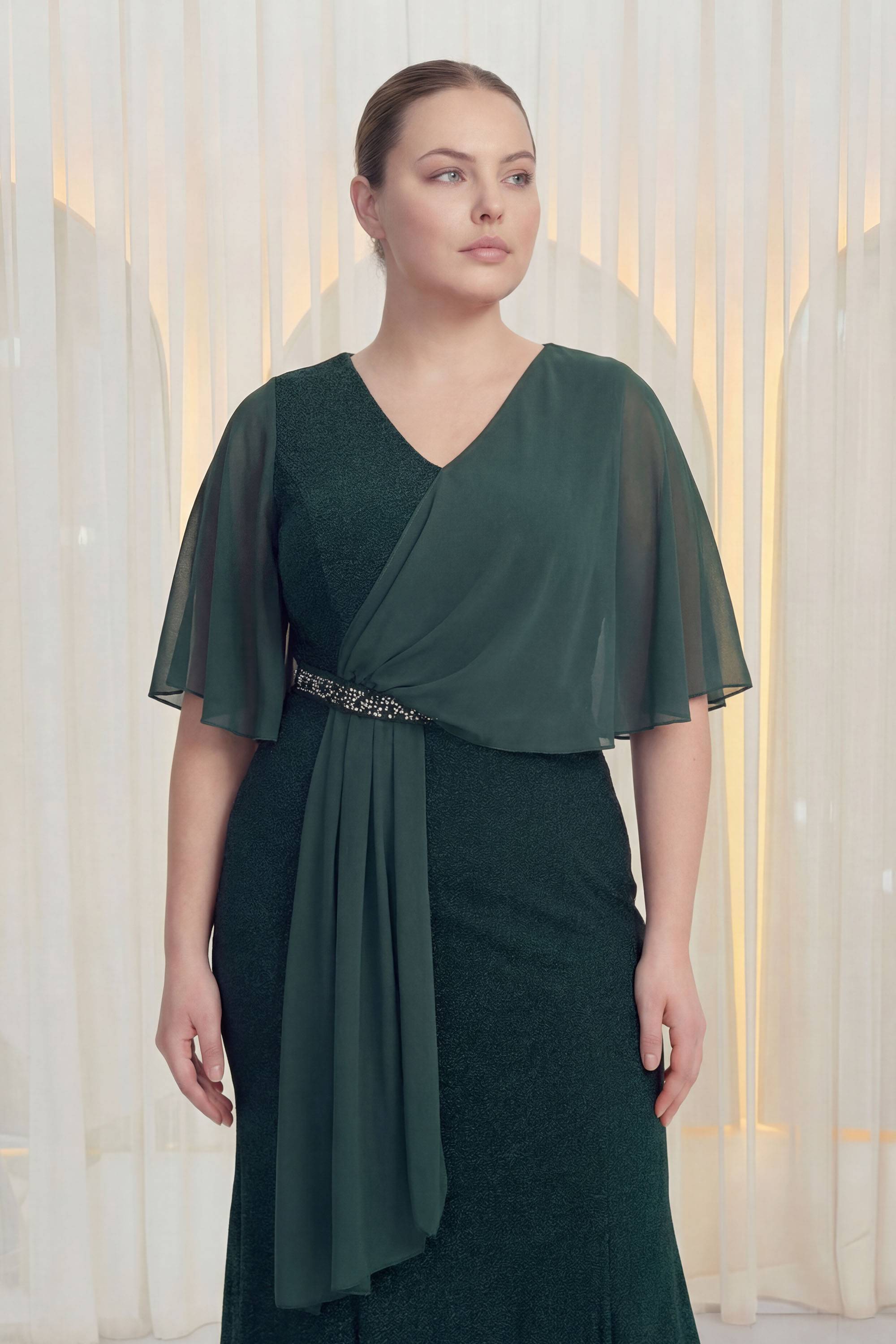 The ZKS büyük beden şifon kol abiye elbise, zümrüt yeşili, yandan görünüm, V yaka ve taşlı kemer detayı