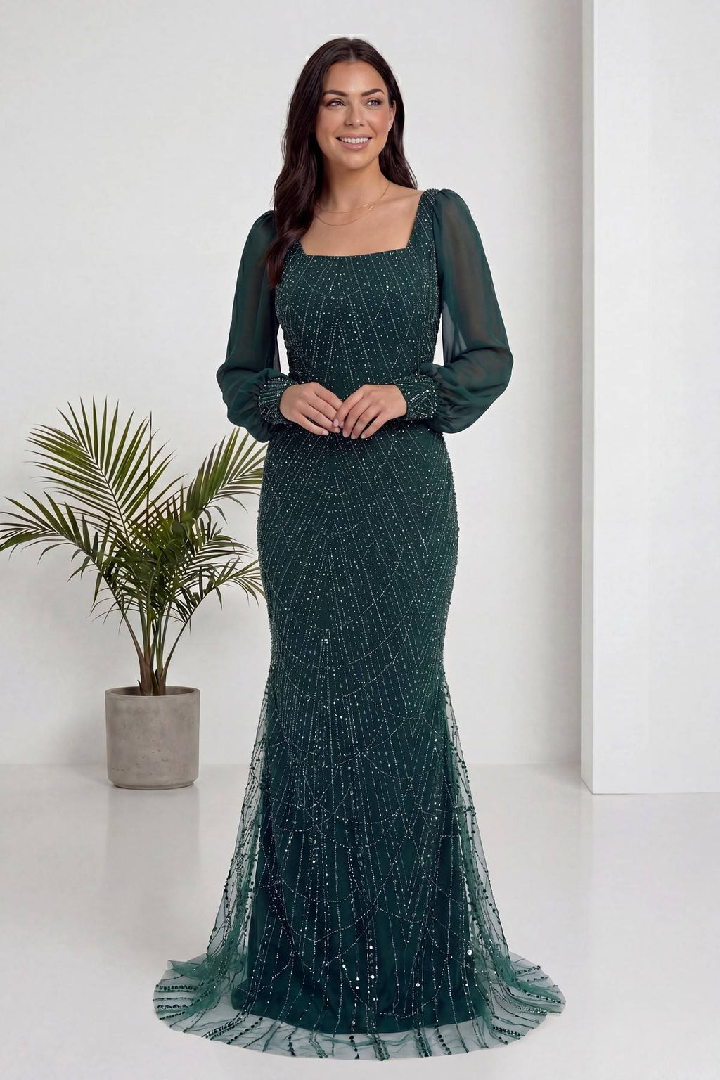 The ZKS yeşil kare yaka şifon balık abiye, ön cepheden elleri belinde zarif bir poz